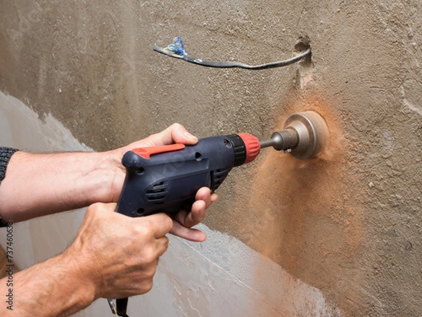 Obraz Drilling a socket in a brick wall, a drill for a socket, a worker doing electrical repairs