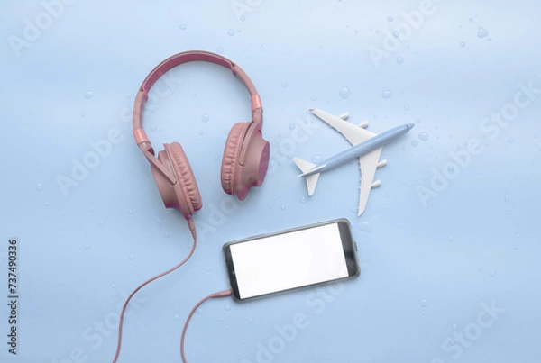 Obraz Top view, red musical headphones in water drops, with airplane travel concept, copy space. Headphones on a blue background on a wet surface on a blue background. Place for text. Background audio mp3.