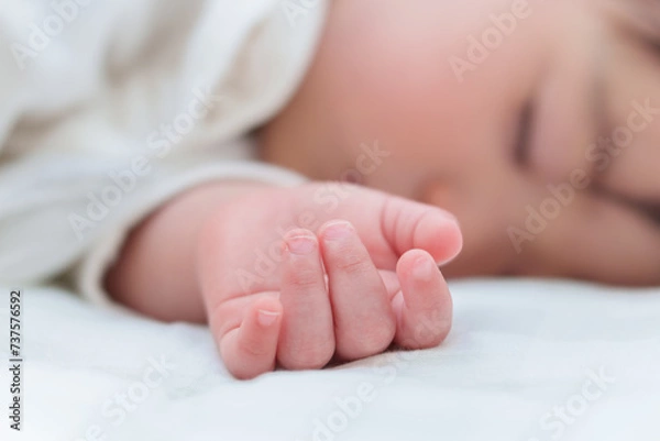 Fototapeta ベッドでお昼寝する赤ちゃんの手