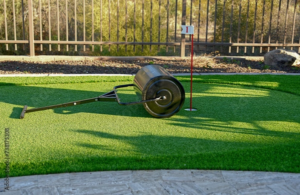 Fototapeta A sod roller on an artificial turf backyard putting green.