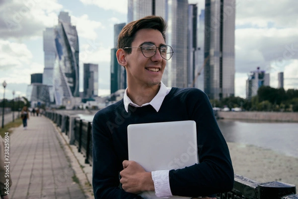 Obraz Good grades. A young attractive student is happy about going to college. A guy is walking in the city.