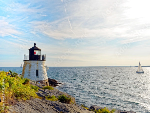 Fototapeta Castle Hill Lighthouse in summer, a beautiful and famous New England light house, Newport, Rhode Island, USA with a sailboat in the distance in Narragansett Bay.