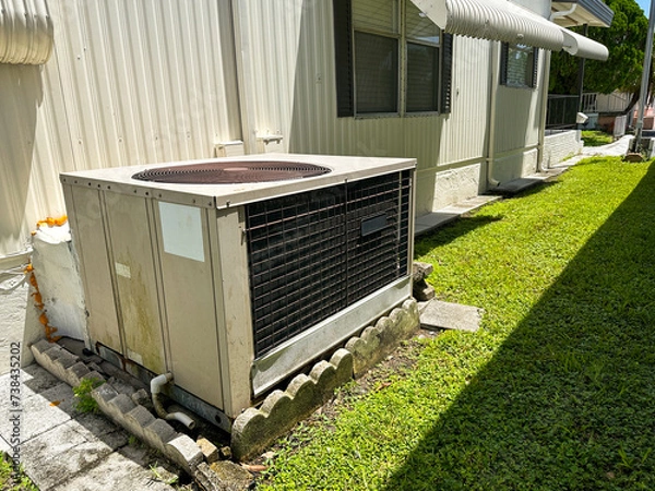 Fototapeta Outdoor HVAC unit installed beside a mobile home, highlighted by the bright sunshine on a clear day. Spilt type air-conditioning.