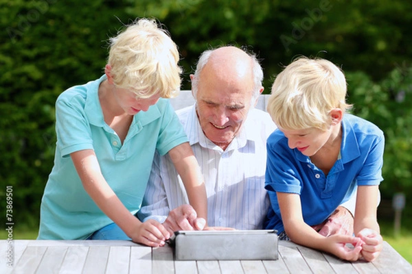 Fototapeta Two brothers teaching grandpa to use tablet pc