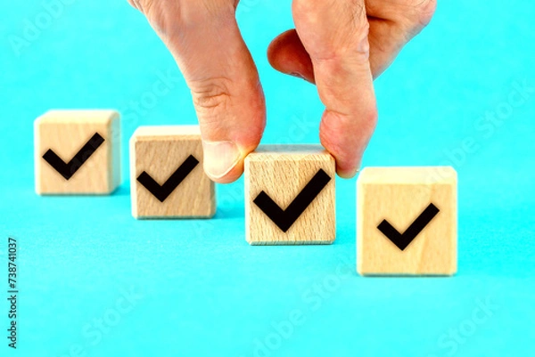 Fototapeta  Check mark on wooden blocks, blue background with copy space.