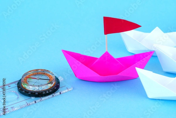 Fototapeta Paper Boats With Compass. paper ship leading among group of ships on background.