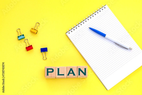 Fototapeta Notepad and pen on the background. Wooden cubes with word plan.