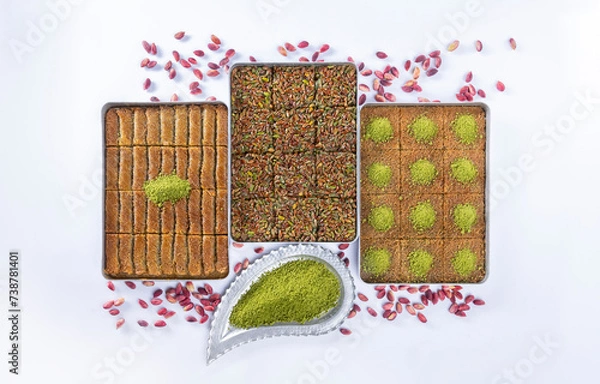 Fototapeta Top view of shredded phyllo dough dessert species with pistachio on trays isolated on white background. Local name is kadayıf which is a traditional Turkish cuisine dessert with pistachio and sherbet.