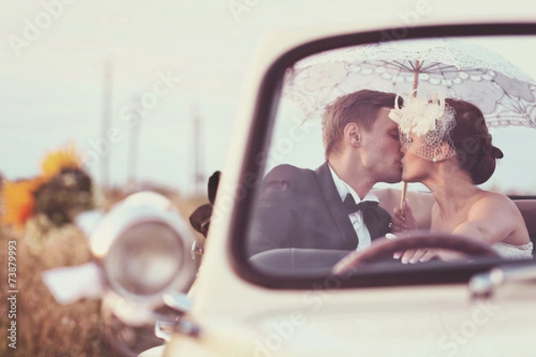 Fototapeta Bride and groom in a vintage car