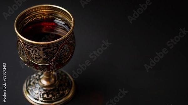 Fototapeta An ornate wine cup used in the Kiddush ceremony at the beginning of the holiday, filled with red wine. black background