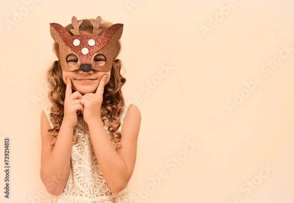 Fototapeta Unique child. Happy child in deer costume. Little cute girl in a carnival masquerade deer mask made of foamiran. The child is preparing to celebrate festival.