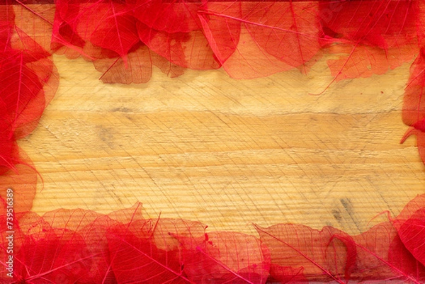 Fototapeta frame of red painted leaves on wooden background with space for text