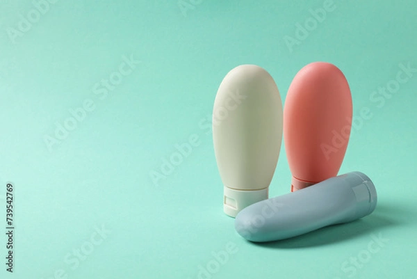 Fototapeta Cosmetic travel kit on turquoise background. Space for text