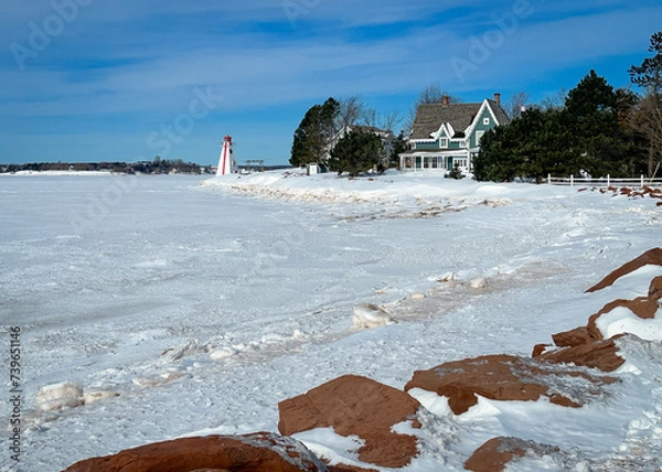 Fototapeta A lighthouse on the edge of the frozen water in winter. 