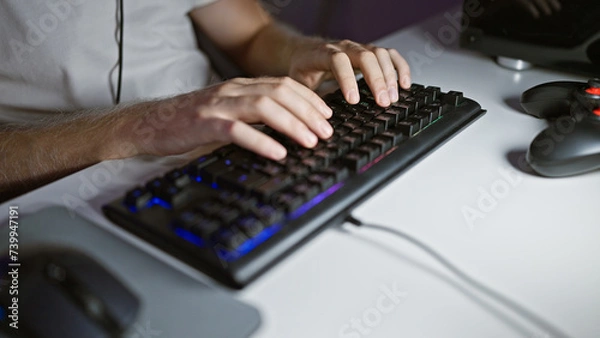 Fototapeta Caucasian man typing on a backlit keyboard in a dark room at night, showing a focus on technology and modern home office.