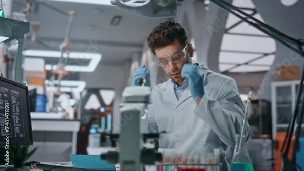 Fototapeta Scientist putting safety glasses working with samples in laboratory close up.