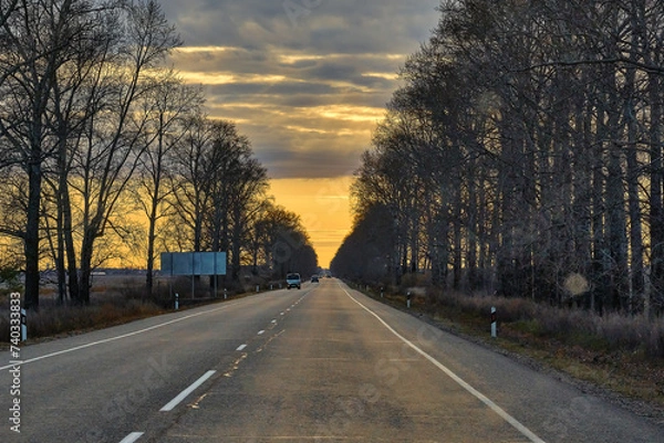 Fototapeta A beautiful sunset on the background of an asphalt road leading to the city of Blagoveshchensk in Russia.
