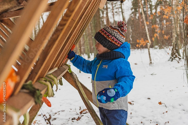 Obraz child in winter forest feeding animals
