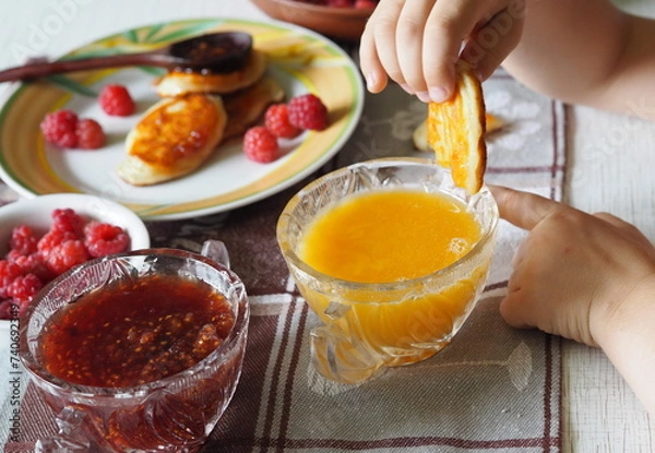Fototapeta Summer children is breakfast. The child eats pancakes with honey with his hands. Baby food and allergies.