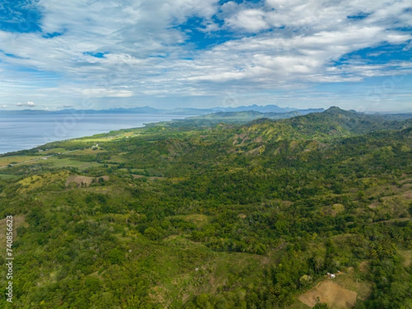 Fototapeta Aerial view of Mountains covered rainforest, trees and blue sky with clouds. Mindanao, Philippines.