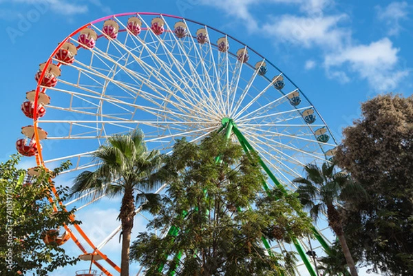 Fototapeta View of a Ferris wheel with colorful gondolas in Ayia Napa fun park. Cyprus, Mediterranean sea.