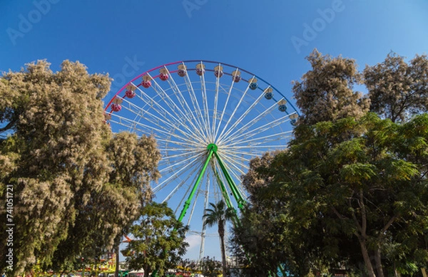 Fototapeta View of a Ferris wheel with colorful gondolas in Ayia Napa fun park. Cyprus, Mediterranean sea.