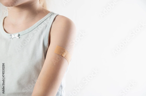 Fototapeta Plaster on the hand of a girl child after vaccination against influenza and whooping cough. Copy space for text. Revaccination against infections