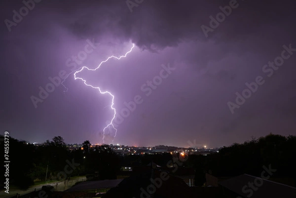 Fototapeta Stunning lightning strikes just before an incredible thunderstorm over a suburban home area. Showing the absolute strength that exists within nature