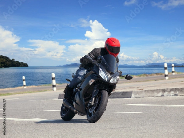 Fototapeta young man riding big bike motorcycle against sharp curve of asph