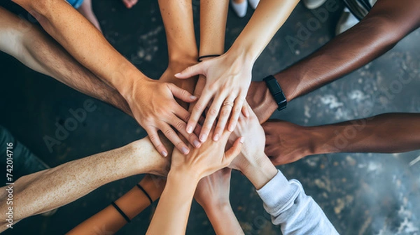 Fototapeta Diverse people form a circle, holding hands, hands piled symbolizing teamwork, team building, collaboration, unity and inclusion 