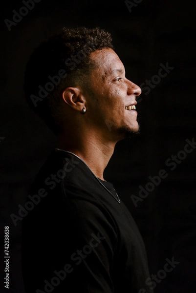Obraz Low key portrait of young African man in profile smiling