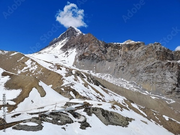 Obraz Snowy mountain stands tall amidst white landscape, as a lone cloud floats lazily in the bright blue sky.