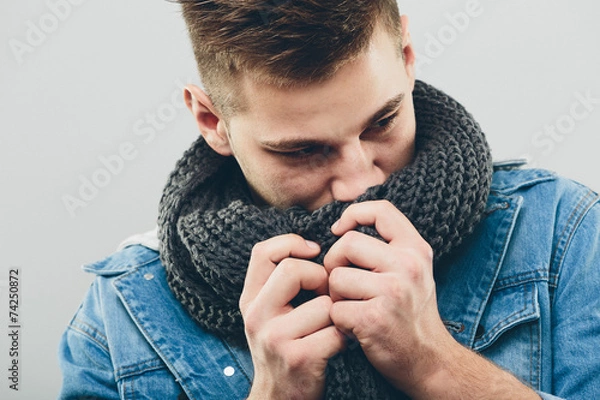 Obraz Przemyślany przystojny mężczyzna wącha jego szalik z dzianiny