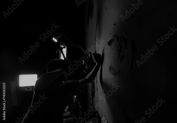 Fototapeta a man is hammering nails into a wall on a black and white background