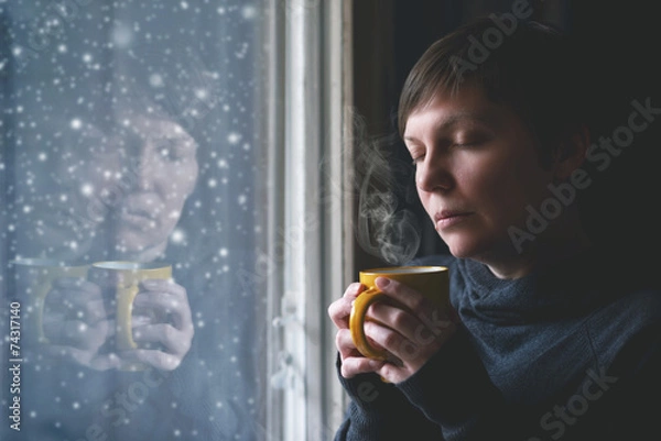 Obraz Samotna kobieta pije kawę w ciemnym pokoju