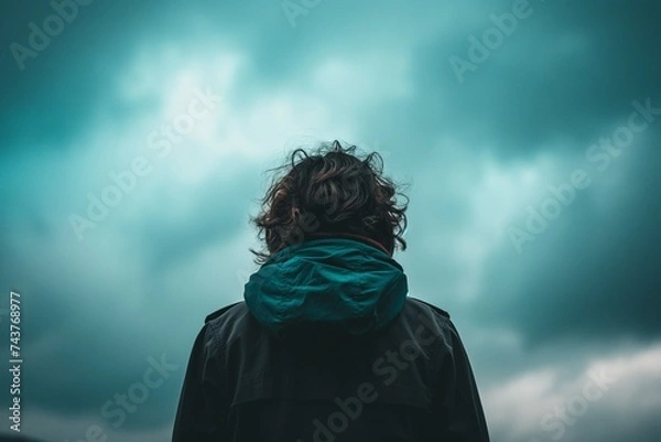 Fototapeta portrait of a person in a hood standing under the gloomy sky.