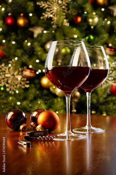 Fototapeta Glasses of red wine on table with Christmas tree