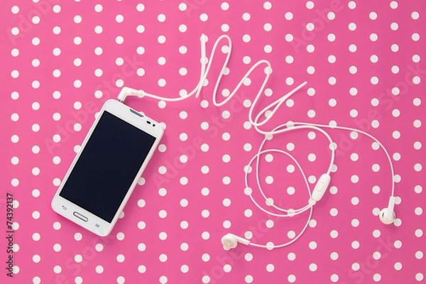 Fototapeta Small headphones with mobile phone on pink vintage paper with do