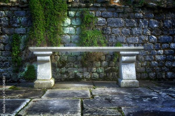 Fototapeta a white stone bench in from of a wall