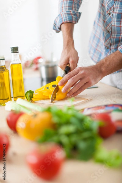 Fototapeta closeup on man's hands cutting vegetables