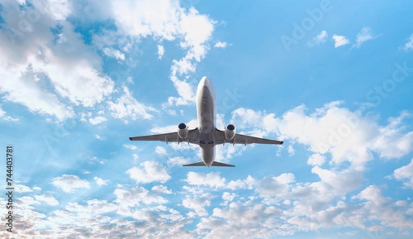 Fototapeta White passenger airplane flying in the sky amazing clouds in the background - Travel by air transport