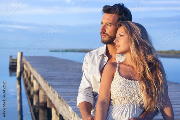 Fototapeta man embracing his woman from behind on seaside background under