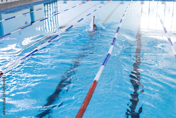 Obraz Swimmers practice in an indoor pool, focusing on their strokes