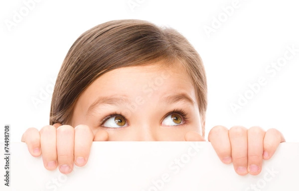 Fototapeta Little girl is looking from out blank board