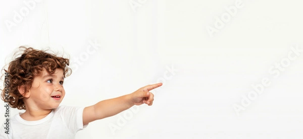 Fototapeta A little boy points his finger on an isolated light-colored background with free space generated AI