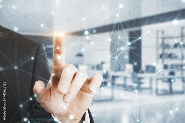 Fototapeta A professional businessman in a suit reaches out to touch a futuristic digital network interface in a corporate environment