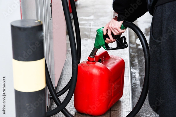 Obraz A man pouring fuel into a canister at a gas station.