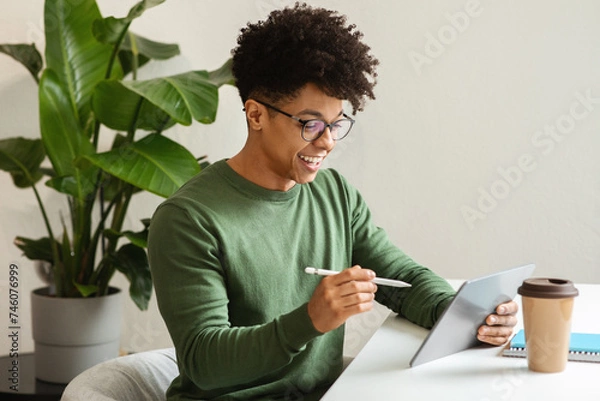 Fototapeta Stylish african american guy using digital tablet, drinking coffee