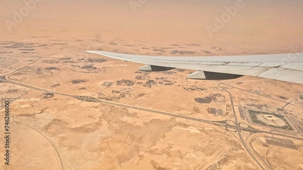 Obraz An airplane is flying over a desert landscape