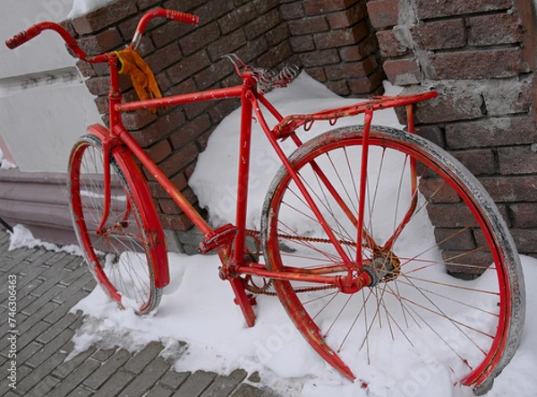 Fototapeta An old bike of bright red color abandoned on a city street. An art installation in the form of an old, forgotten, broken bicycle.